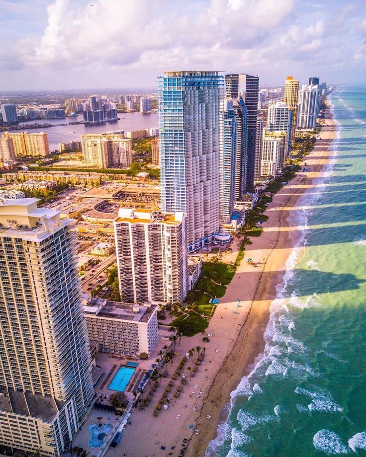 A view of the ocean from above shows buildings and beach.