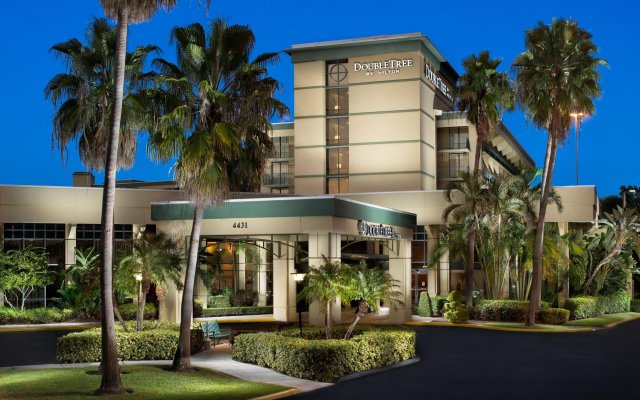 A hotel with palm trees and bushes around it.