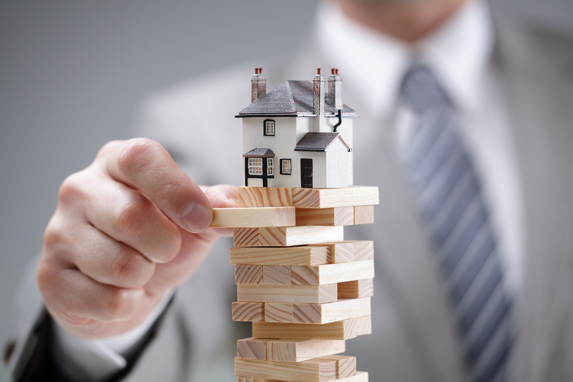 A man is playing with wooden blocks and houses.