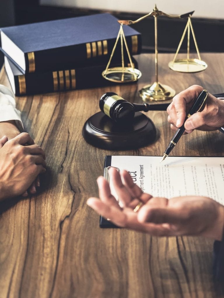 A man is sitting at the table with his hands on a pen and paper.