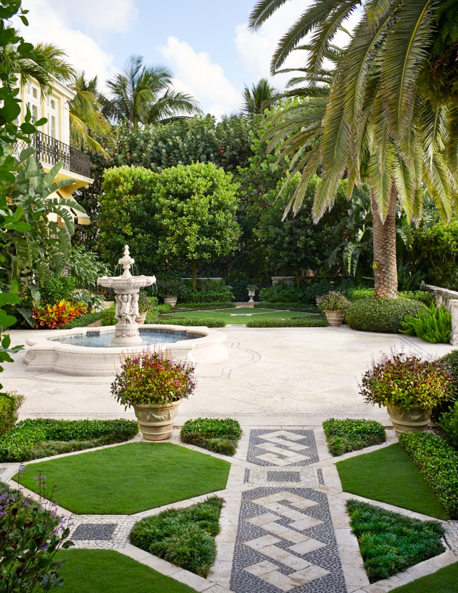 A garden with a fountain and palm trees.